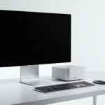 ミニマルな白いデスク上に置かれたApple Mac Studioデスクトップコンピューターと大型モニター