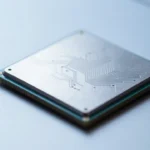 ノートPCのマザーボード上に置かれた小型AIアクセラレータチップのマクロ撮影風カット。銀色のヒートスプレッダーと基板の回路パターンを強調した、落ち着いた青系照明の製品写真